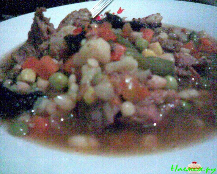 Говяжий суп с фасолью, овощами и черносливом в керамической посуде