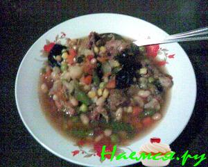 Говяжий суп с фасолью, овощами и черносливом в керамической посуде