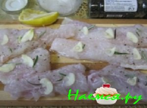 Зубчики чесночка почистить, тщательно вымыть и аккуратно порезать их лепестками, выложить их на рыбу.