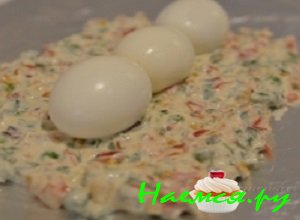 На пишевую пленку либо фольгу выложить содержимое салатницы, аккуратно распределить массу в форме прямоугольника. Посередине выложить три вареных куриных яйца 