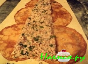 По центру блинной основы выложить половину мясной начинки в форме узкой трапеции таким образом, чтобы краешки блинчиков оставались свободными от начинки