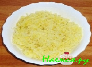 Картофельные клубни очистить и отварить их до готовности, после чего охладить до комнатной температуры и натереть на терке крупного размера.