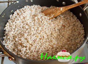 Потом в скороду с луком отправьте готовую перловую крупу, посолите, поперчите ингредиенты и перемешайте